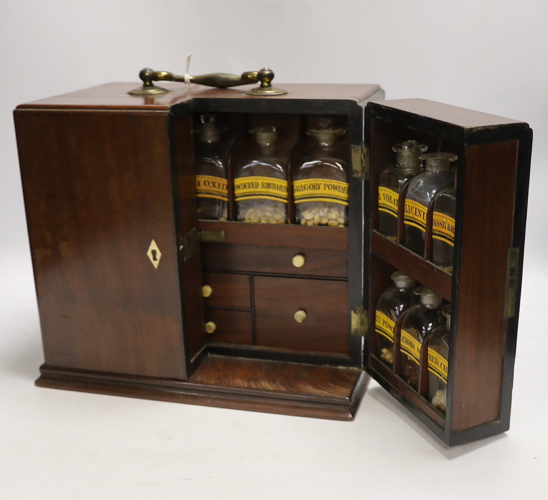 A Georgian mahogany domestic medicine chest, with bone drawer knobs and escutcheons, containing a number of glass square section drug bottles, fitted drawers containing scales, a pestle and mortar, etc., 29cm wide, 25cm